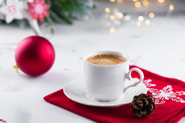 Obraz na płótnie Canvas Cup of espresso or americano coffee in white cup in cosy Christmas arrangement, festive decoration with bokeh background, copy space