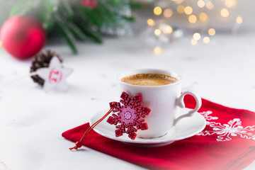 Cup of espresso or americano coffee in white cup in cosy Christmas arrangement, festive decoration with bokeh background, copy space