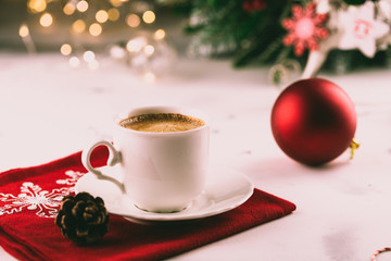 Cup of espresso or americano coffee in white cup in cozy Christmas arrangement, festive decoration with bokeh background, copy space