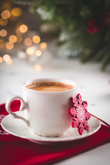 Cup of espresso or americano coffee in white cup in cozy Christmas arrangement, festive decoration with bokeh background, copy space