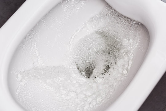 Flush toilet. Water flushes the toilet. The flow of water is clearly visible.