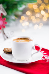 Cup of espresso or americano coffee in white cup in cozy Christmas arrangement, festive decoration with bokeh background, copy space