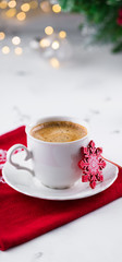 Cup of espresso or americano coffee in white cup in cozy Christmas arrangement, festive decoration with bokeh background, copy space