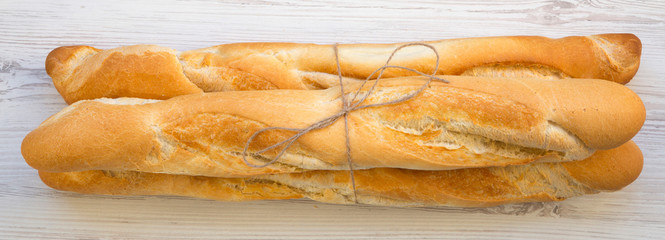 Fresh french baguettes on white wooden surface, toverhead view. Close up.