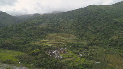 Fototapeta premium Aerial view of rice fields and agricultural land on the slopes of the mountains. Mountains covered forest, trees. Cordillera region. Luzon, Philippines.