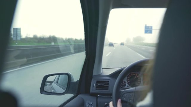 female hands on the steering wheel while the car is moving. Woman behind the wheel. Drives over German highway