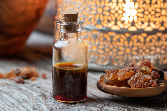 A bottle of myrrh essential oil with myrrh resin on a table