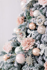 Obraz na płótnie Canvas Decorated Christmas tree in rustic and shabby chic style. New Year scene. Close-up. Christmas tree and christmas decorations pink and gold color in white interior.