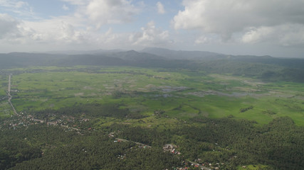Fototapeta premium Mountain valley with river, farmland, rice fields. Aerial view of Mountains with green tropical rainforest, trees, jungle with sky. Philippines, Luzon.