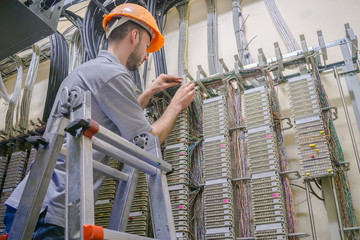  The engineer works in the server room of the data center. Cable laying in telephone exchange. A...