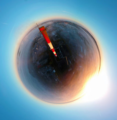 Aerial little planet 360 view on brick chimney in city covered in white fog during sunrise.