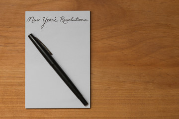 New Year's Resolutions On Blank Notepad With Pen