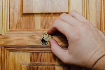 The hand deflects the metal eyepiece, the peephole in the door. The concept of peeping, checking...
