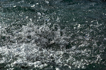 Fototapeta na wymiar The sea surface is covered with splashes from drops of a strong pouring rain, a close-up of liquid splashes.