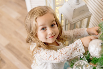 Fototapeta premium happy girl decorates the Christmas tree
