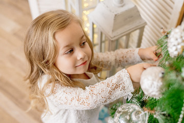 happy girl decorates the Christmas tree