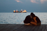 Rear view of couple sitting on dock at sunset