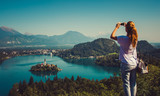 Woman taking picture of Lake Bled with smartphone