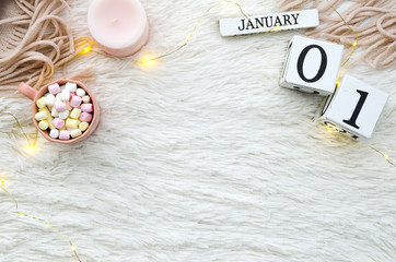 Warm cozy home start new year 1 january on perpetual calendar. Copy space and cup of coffee with marshmallows, candle. Flat lay top view