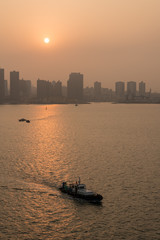 Fototapeta premium Sun rising behind the tall city skyline of Qingdao in China