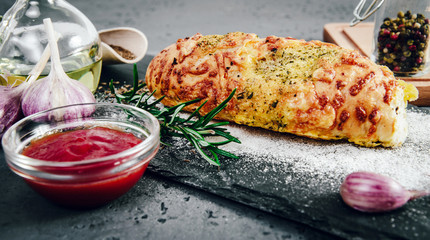 Freshly baked bread roll with herbs. Baking rolls and bread. Delicious bread with herbs on a stone, dark countertop. Adding toppings to buns, bread.