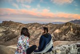 Rear view of women talking with each other while sitting on rock