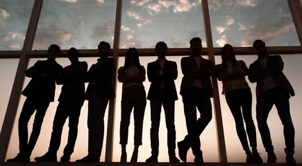 silhouette of a group of business people standing near the office window