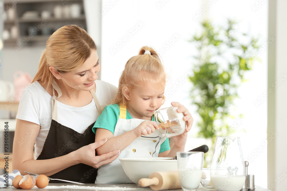 Poster Mother and daughter making dough together in kitchen