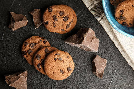 Tasty chocolate chip cookies on dark background, flat lay