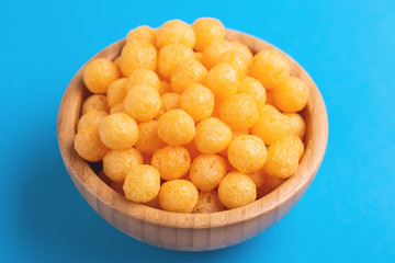 Cheese puff balls in wooden bowl on bright colorful background