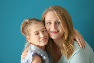 Portrait of happy mother and daughter on color background