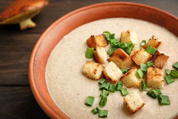 Bowl of fresh homemade mushroom soup on wooden table, closeup