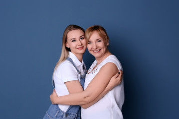 Young woman with her mother on color background