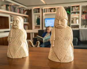 Traditional Lewis Chessmen on table in front of modern library