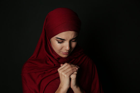 Portrait of Muslim woman in hijab  praying on dark background