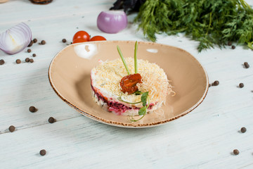 Fresh salad on brown plate on white textured table with cherry tomatoes and chilli and pepper spices and green at background