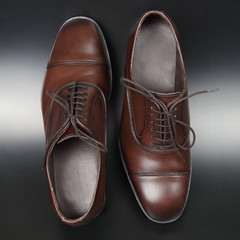 Classic men's brown Oxford shoes on dark background