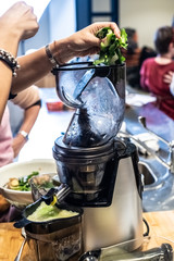 Woman preparing a healthy green juice in a blender.