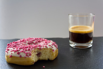 Strawberry Donut with Bite Missing and a cup of espresso coffee