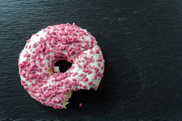 Top view of Donut with white frosting and pink sprinkles and Bite Missing
