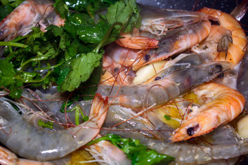 Close up of Raw and fried prawns and coriander cooking in pan