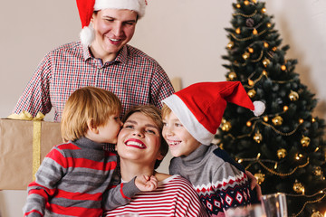 Happy family with two kids hugging each other celebrate Christmas holidays