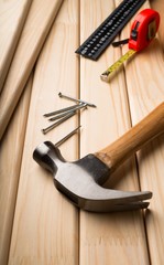Hammer and nails on wood with a measuring tape