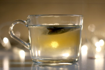 Cup of tea with slice of orange. Selective focus, fairy lights in the background.