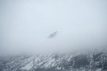 Mountain top surrounded by clouds and fog.