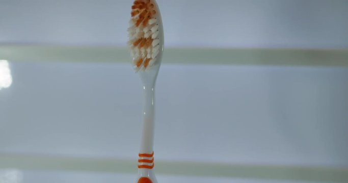 close up shot of a lambda orange and white toothbrush
