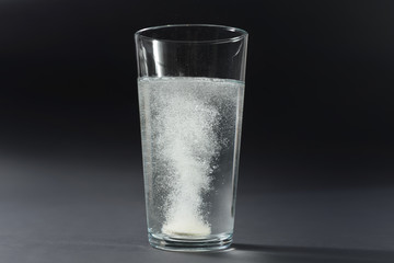 Soluble pill tablet in water with bubbles on black contrasty background