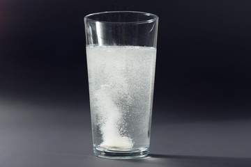 Soluble pill tablet in water with bubbles on black contrasty background