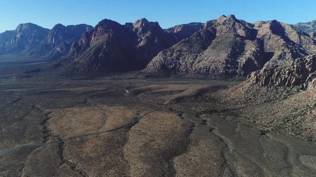 Epic aerial over beautiful desert terrain that pans up to reveal jaw dropping geological rock formations