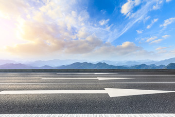 Fototapeta premium Asphalt road and mountains at beautiful sunset